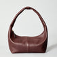 HYER GOODS Everyday Shoulder Bag in burgundy gold with a sleek strap and minimalist design, placed on a neutral background.