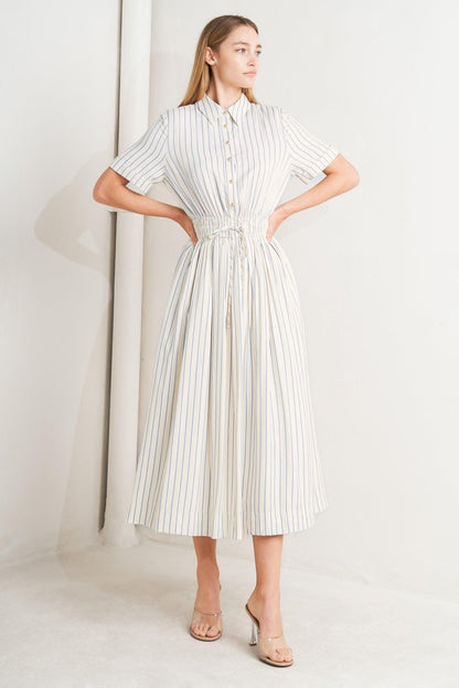 Flying Tomato Sunday Stripe Woven Midi Dress in ivory and blue with a striped pattern, shown hanging on a display.