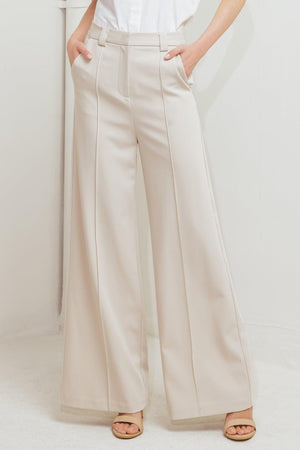 Light beige Flying Tomato Monday Flow woven pants with relaxed fit and textured fabric, displayed on a hanger.