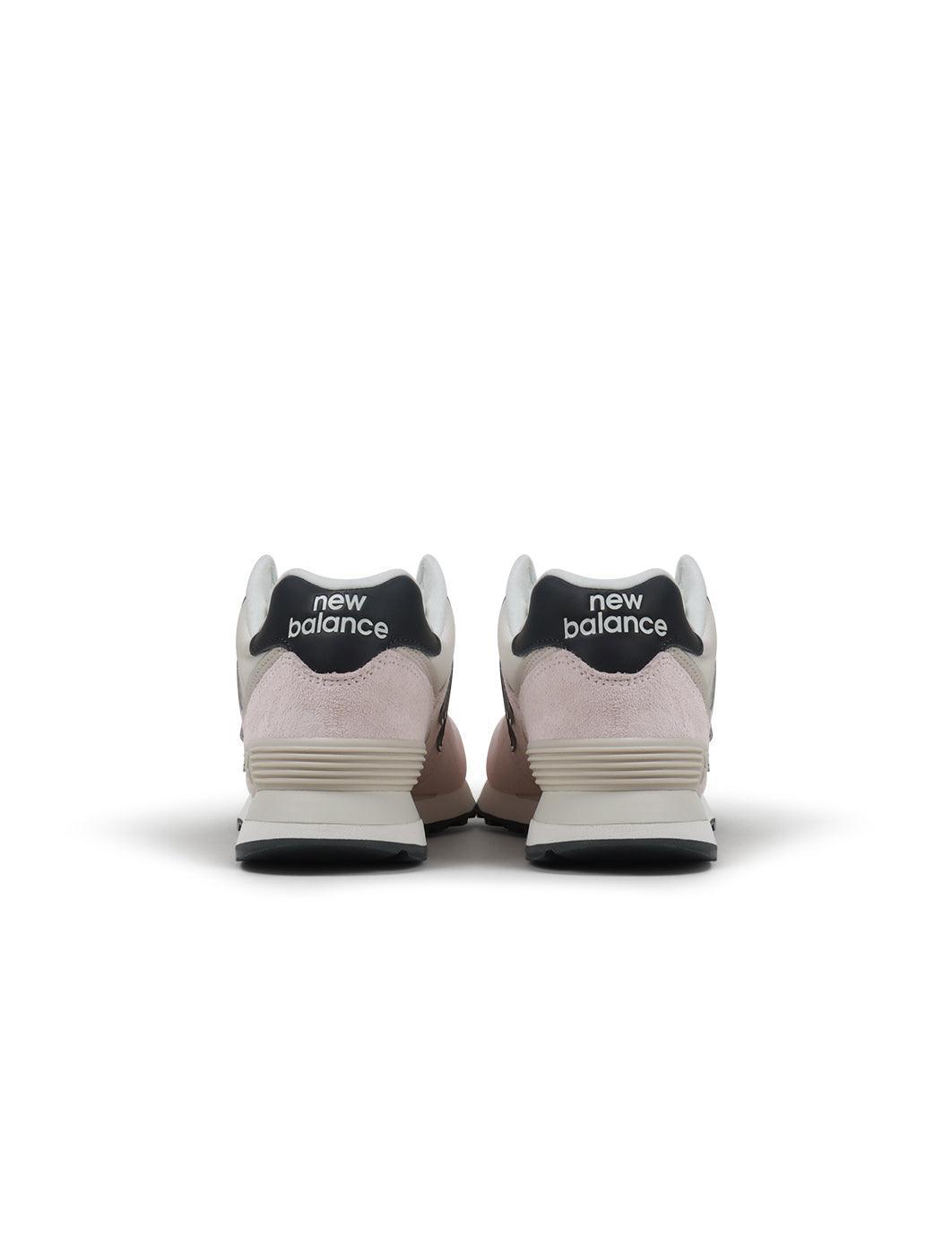 Womens New Balance 574 washed pink sneakers with white soles, casual footwear style, shown from side angle.