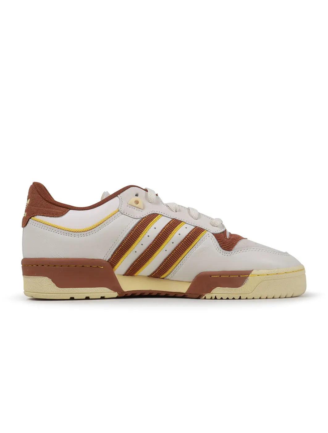 Adidas men's Rivalry Low 86 brown sneakers, low-cut athletic footwear with white accents, on a plain background.