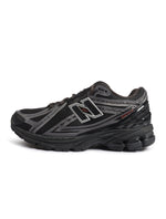Men's New Balance 1906 black and hot tomato athletic footwear with white accents, showcasing the stylish design and comfortable fit.