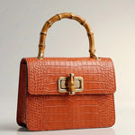 Mini Harriet bag by thebagicon, featuring a compact design with leather details and a top handle, shown in natural light.