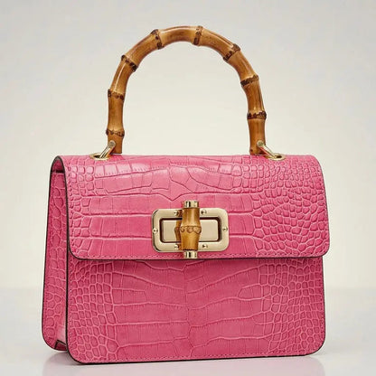 Small black leather handbag, THE MINI HARRIET by thebagicon, with top handle and subtle gold hardware, shown from front view.