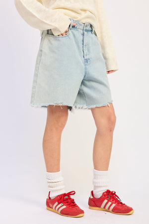 Light denim Riley denim shorts by Emory Park, displayed on a hanger with visible stitching and distressed detailing.