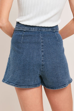 Medium indigo Flying Tomato Sweet Stud denim skort with button and pocket details, styled with a relaxed fit and casual design.