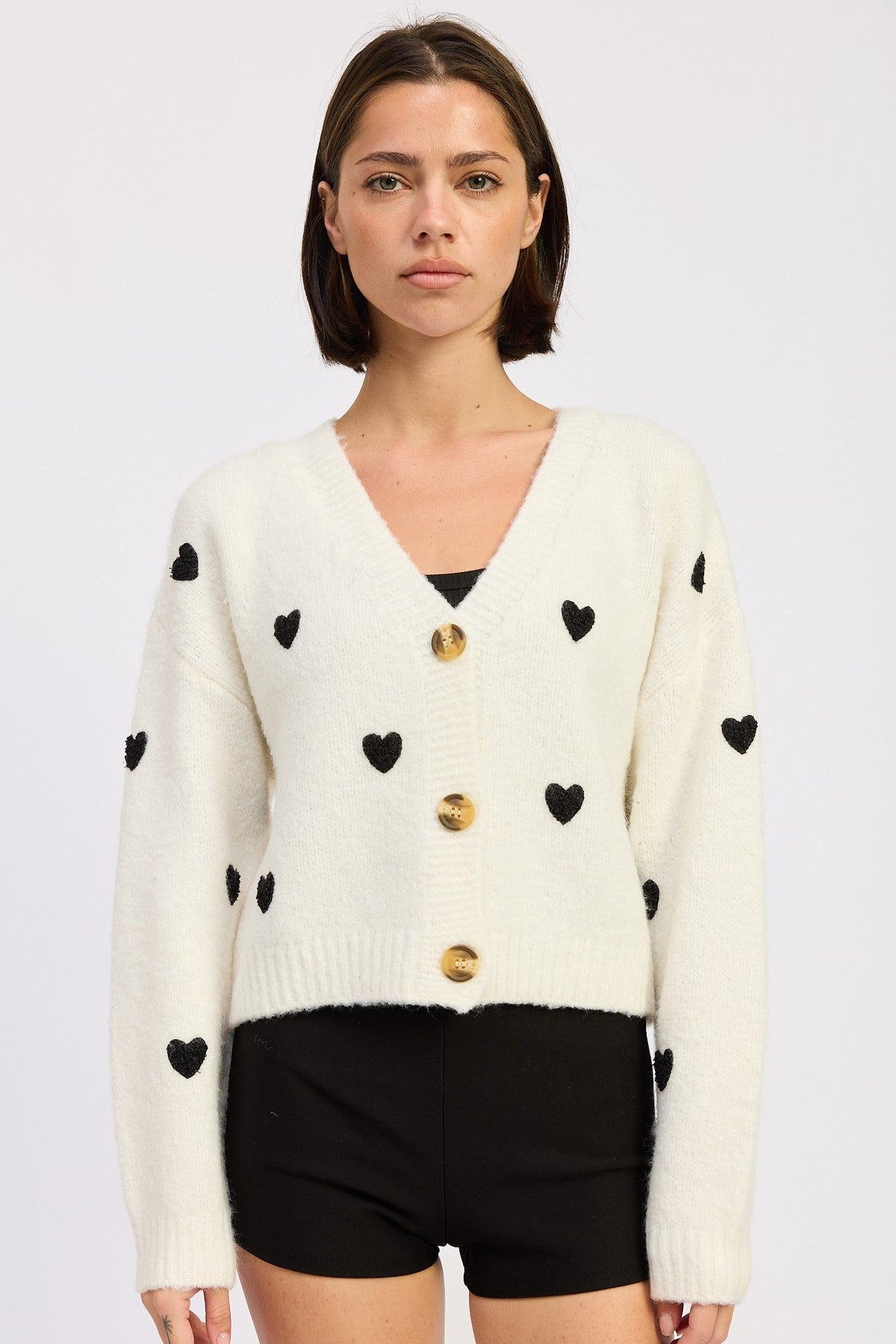 Emory Park Juliette cardigan in ivory and black, lightweight knit with button closure and ribbed cuffs, displayed on a hanger.