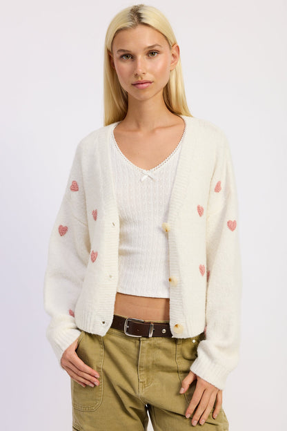 Emory Park Juliette cardigan in ivory pink, soft knit fabric, displayed on a hanger with a button-up front and long sleeves.