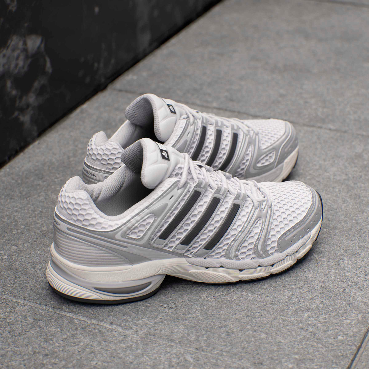 Men's Adidas Adistar Control 5 silver athletic footwear, shown from a side view with mesh and synthetic upper details.
