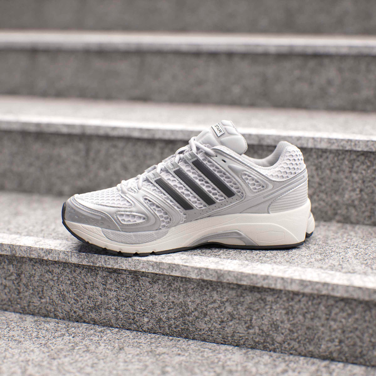 Men's Adidas Adistar Control 5 running shoes in silver, showcasing the sleek design and athletic style of the footwear.