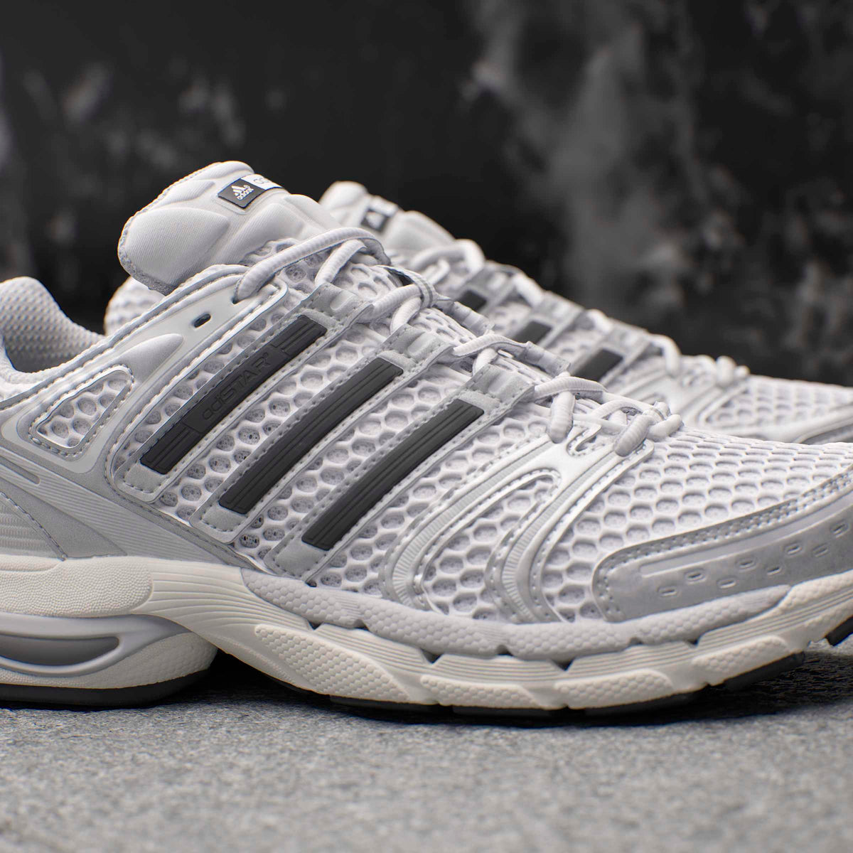 Silver Adidas men's Adistar Control 5 running shoes with breathable mesh and supportive sole, photographed from the side.