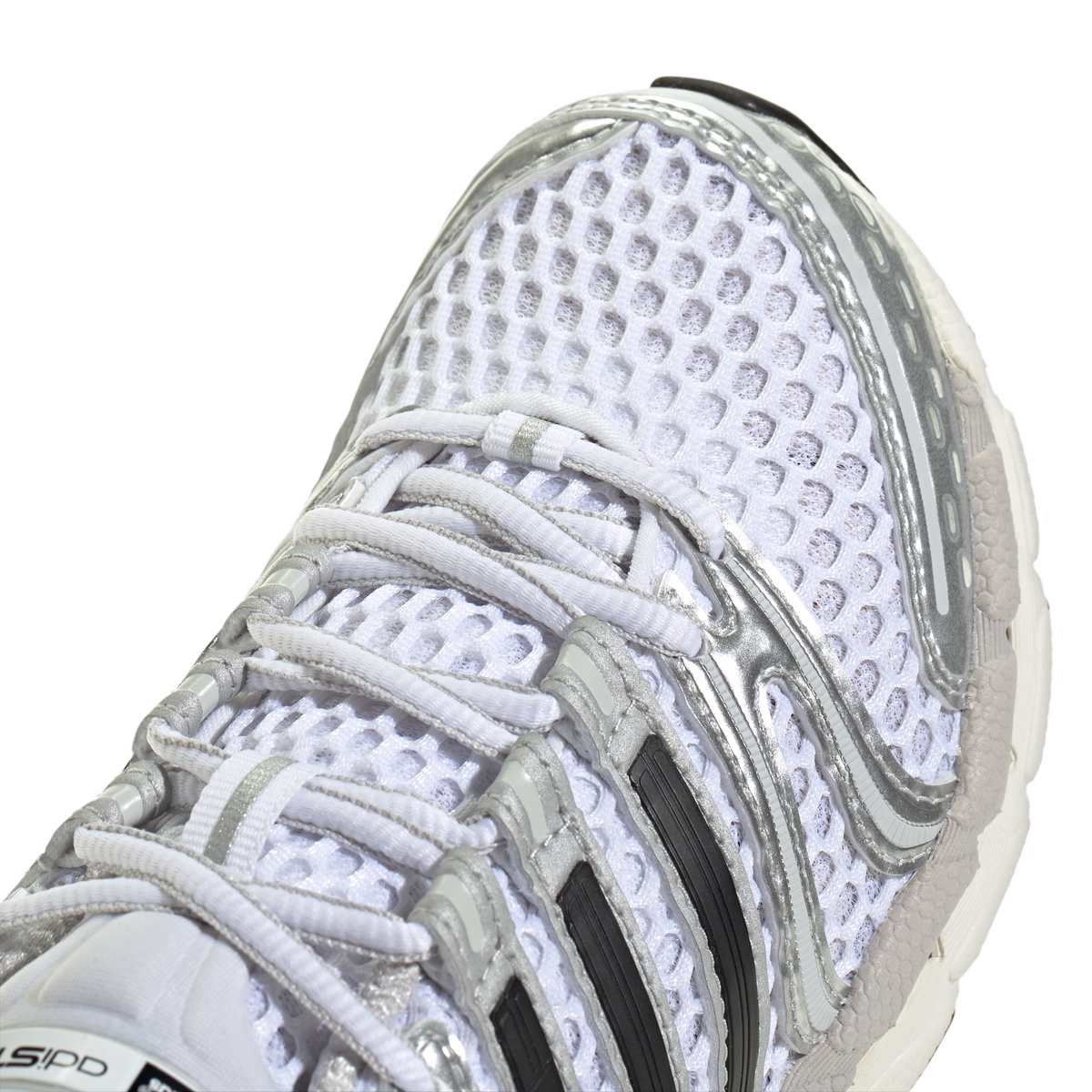 White and silver Adidas Big Kids Adistar Control 5 gradeschool athletic shoes with detailed stitching and Nike branding.