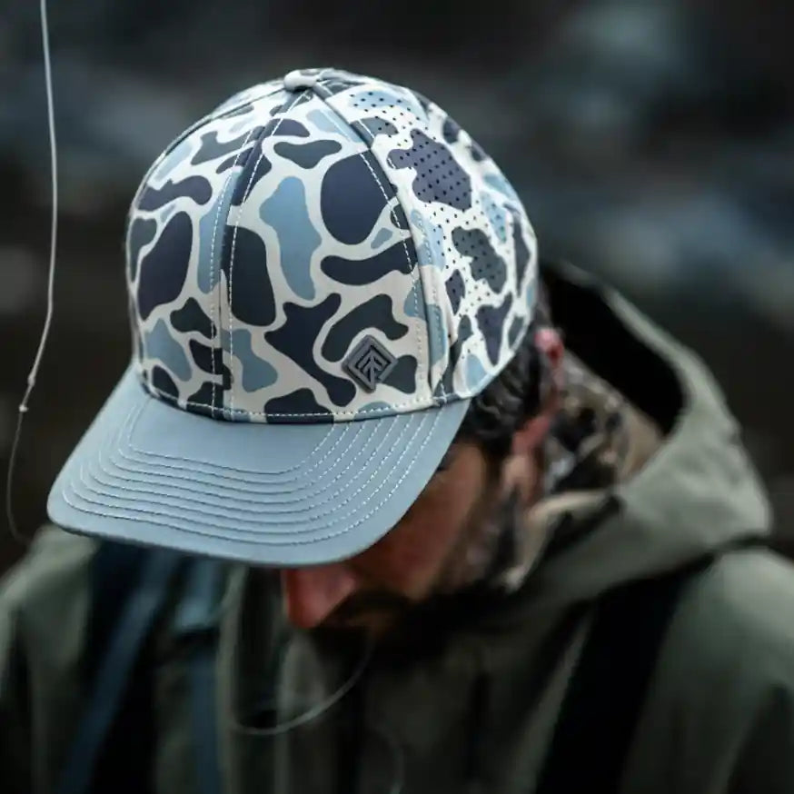 Terreno Hats Ridge Wetland Camo cap with woodland camouflage pattern, adjustable strap, and curved brim for outdoor wear.