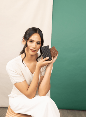 Deux Mains woven card holder from the spring collection, shown with a seated model