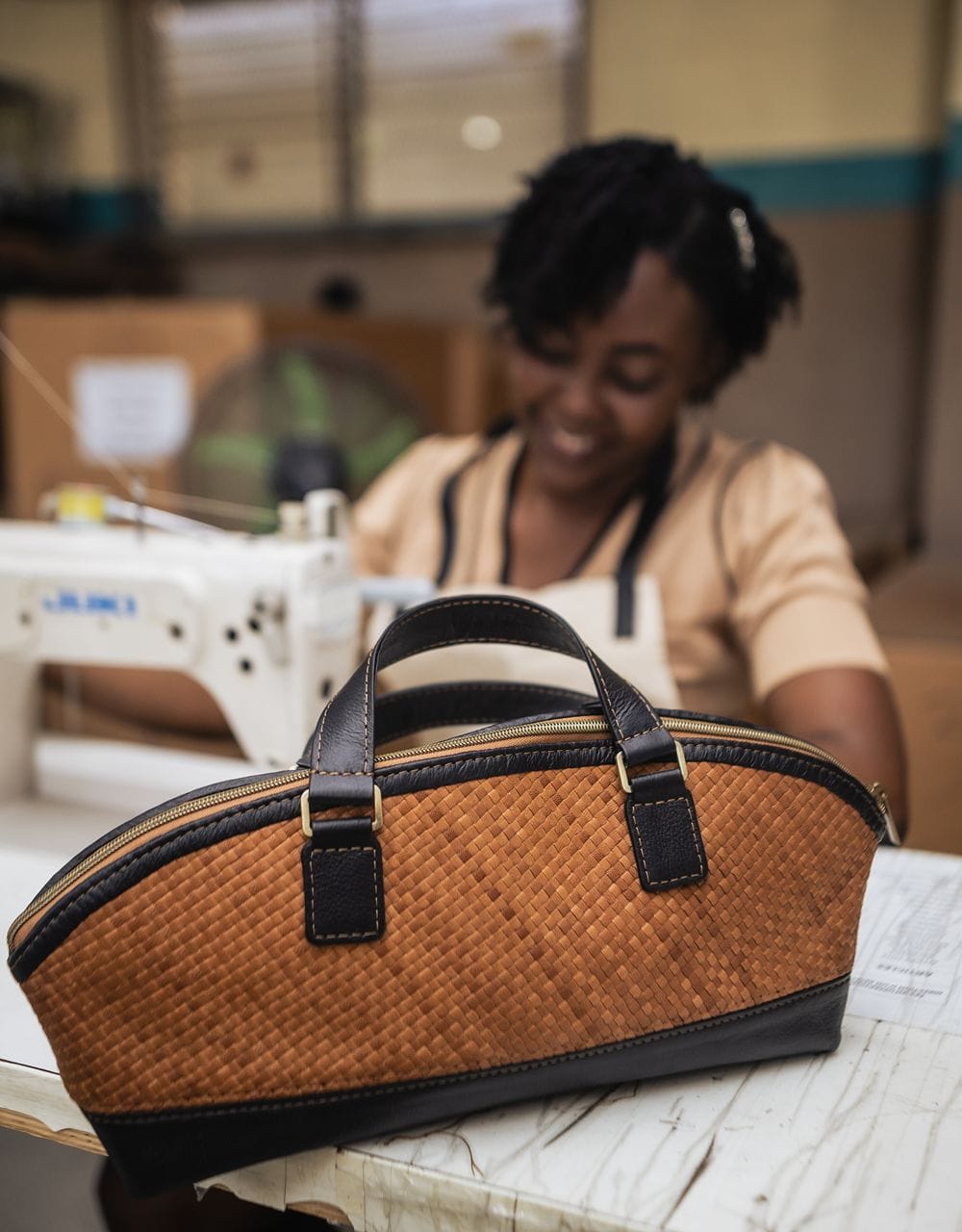 Deux Mains East-West handbag in a sleek horizontal design, crafted in a leather workshop setting
