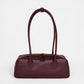HYER GOODS La Strada East West Shoulder Bag in burgundy leather, featuring a sleek design with a top handle and adjustable strap.