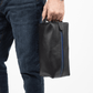 Deux Mains Iron Tight toiletry bag in black and blue, held in hand