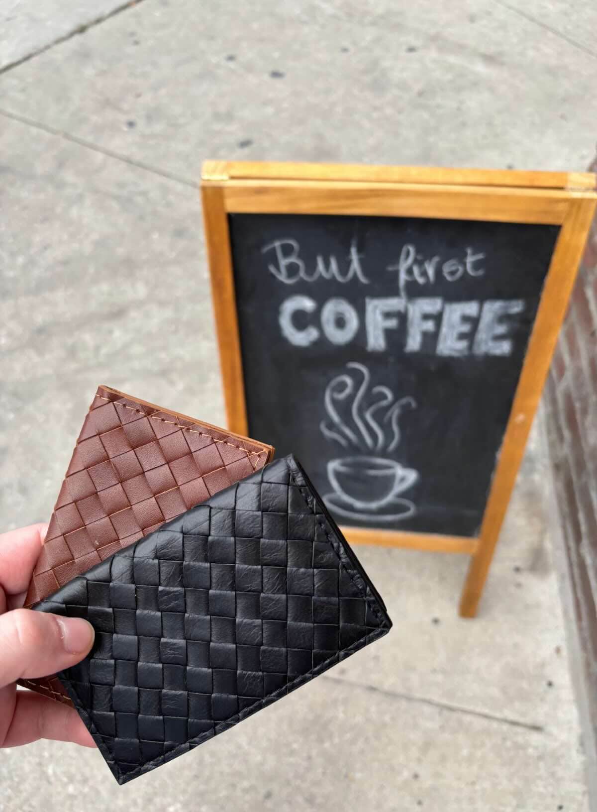 Deux Mains woven card holder in leather, shown with fall accessories in a coffee shop setting